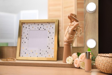 Photo of Frame. golden bijouterie, flowers and bottle of foundation on dressing table