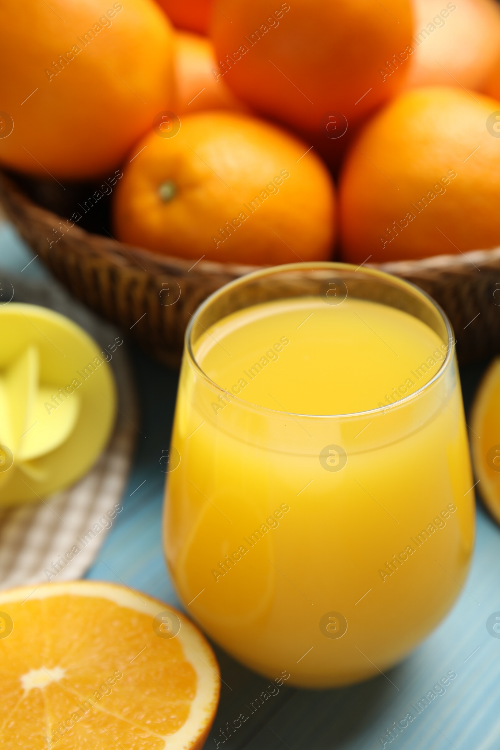 Photo of Freshly made juice, oranges and reamer on blue table