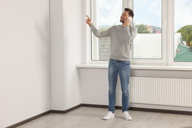 Man talking on phone near window indoors