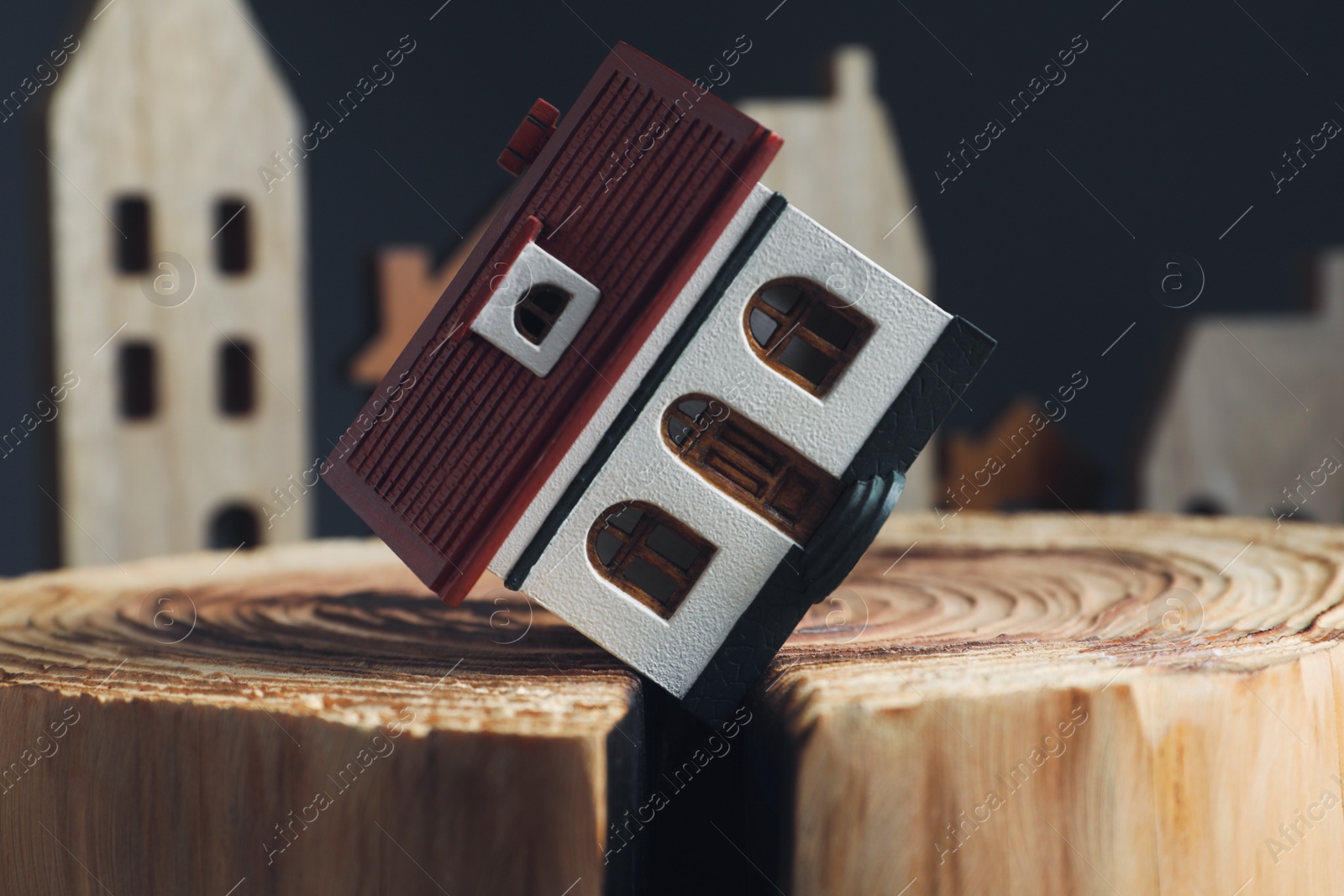 Photo of House model in cracked wooden stump depicting earthquake disaster, closeup