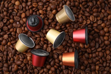 Photo of Many different coffee capsules on beans, flat lay