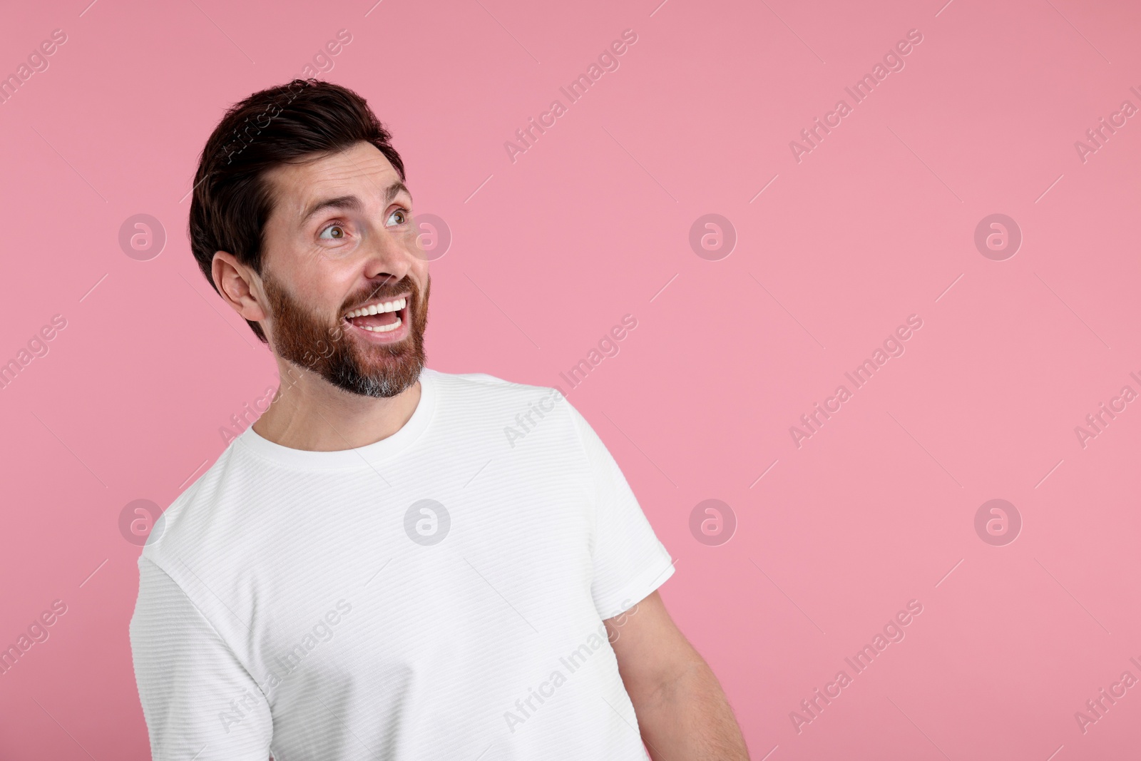 Photo of Portrait of happy surprised man on pink background, space for text