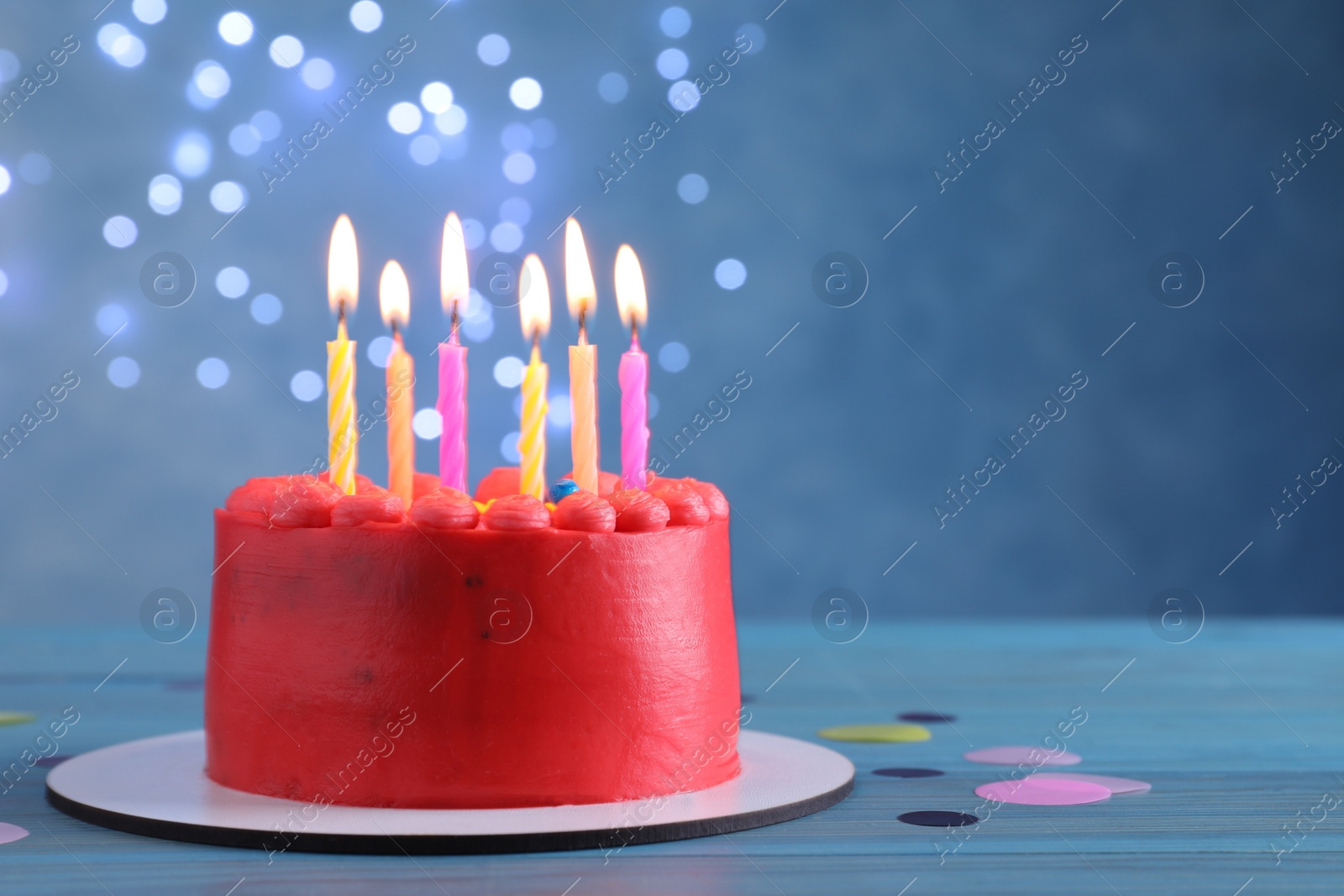 Photo of Cute bento cake with tasty cream and burning candles on light blue wooden table. Space for text