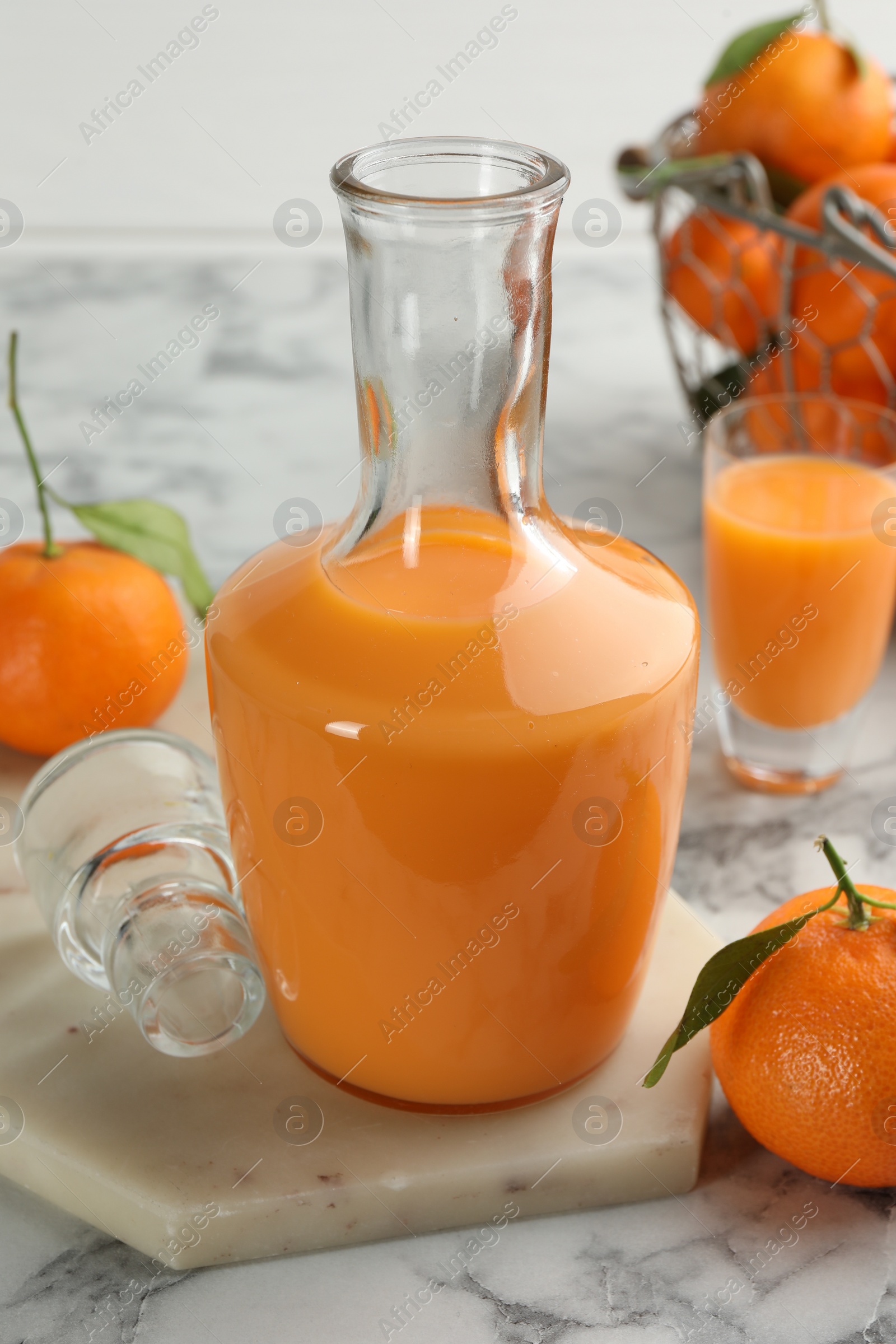 Photo of Delicious tangerine liqueur and fresh fruits on white marble table