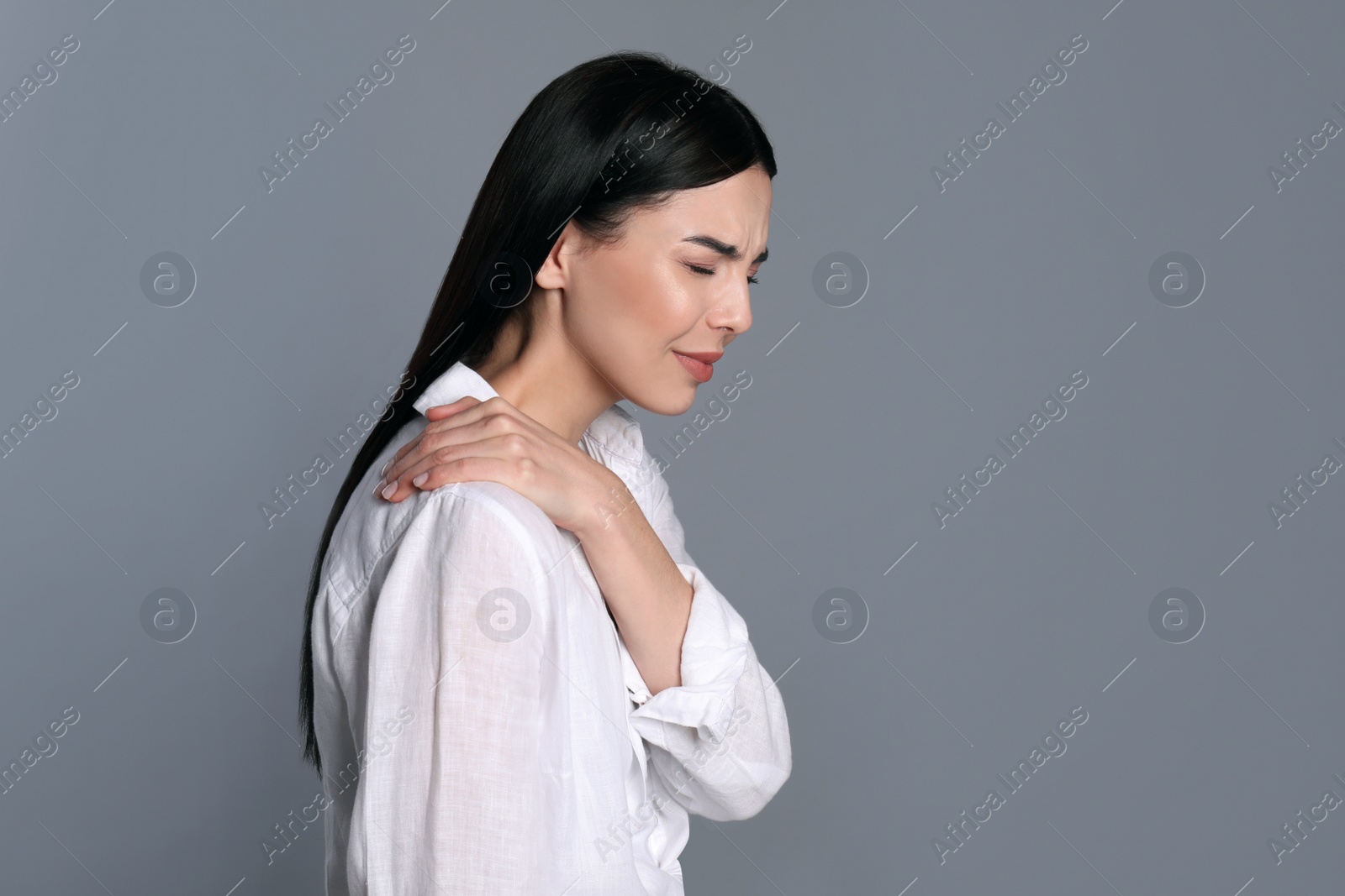 Photo of Woman suffering from shoulder pain on grey background