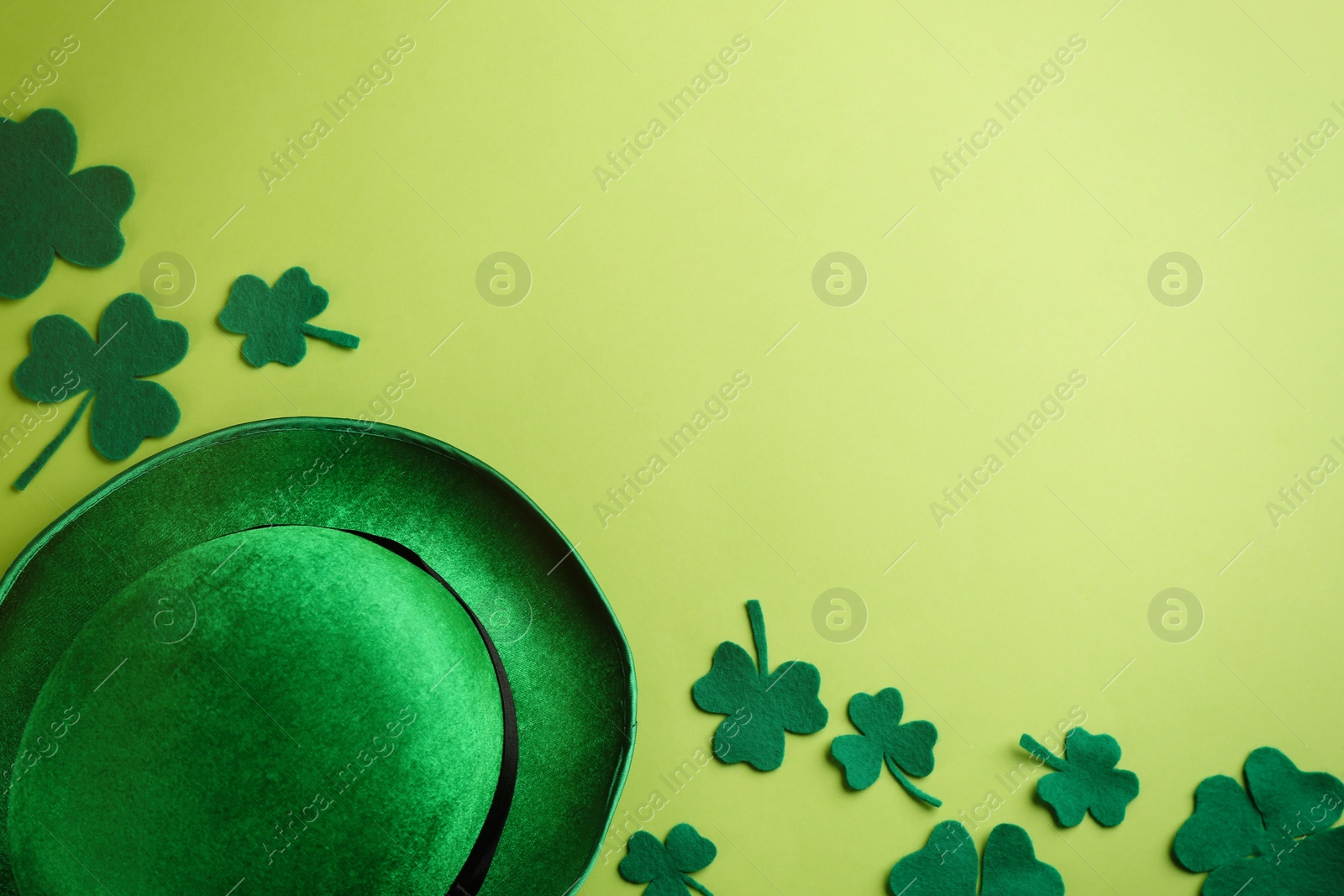 Photo of Leprechaun's hat and decorative clover leaves on green background, flat lay with space for text. St. Patrick's day celebration