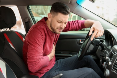 Mature man suffering from heart attack in car