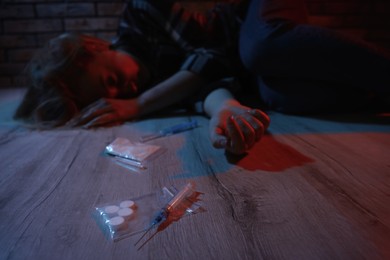 Photo of Addicted woman lying indoors, focus on different drugs