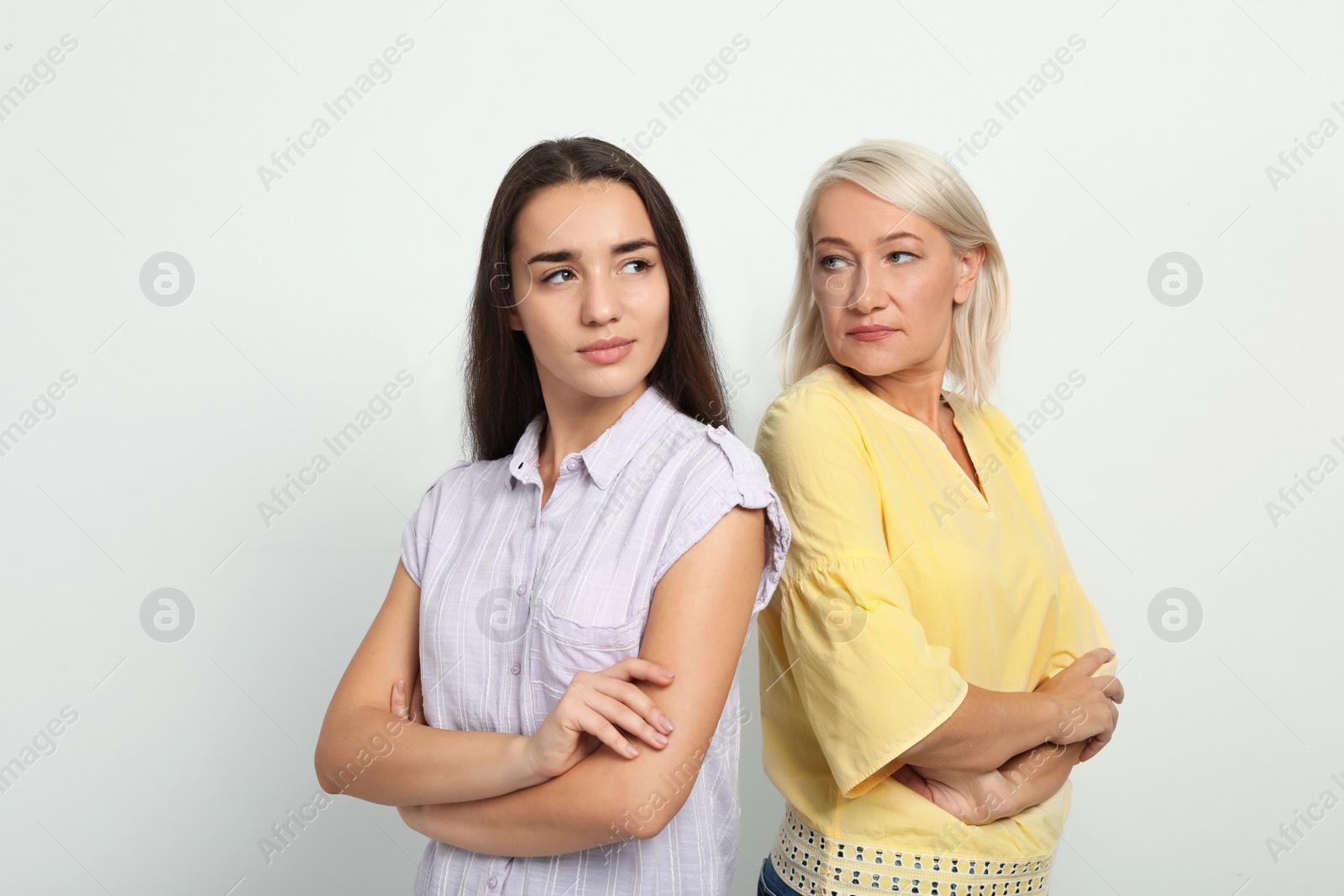 Photo of Portrait of young woman and her mother-in-law on white background. Family quarrel