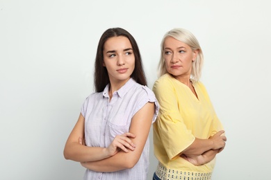 Portrait of young woman and her mother-in-law on white background. Family quarrel