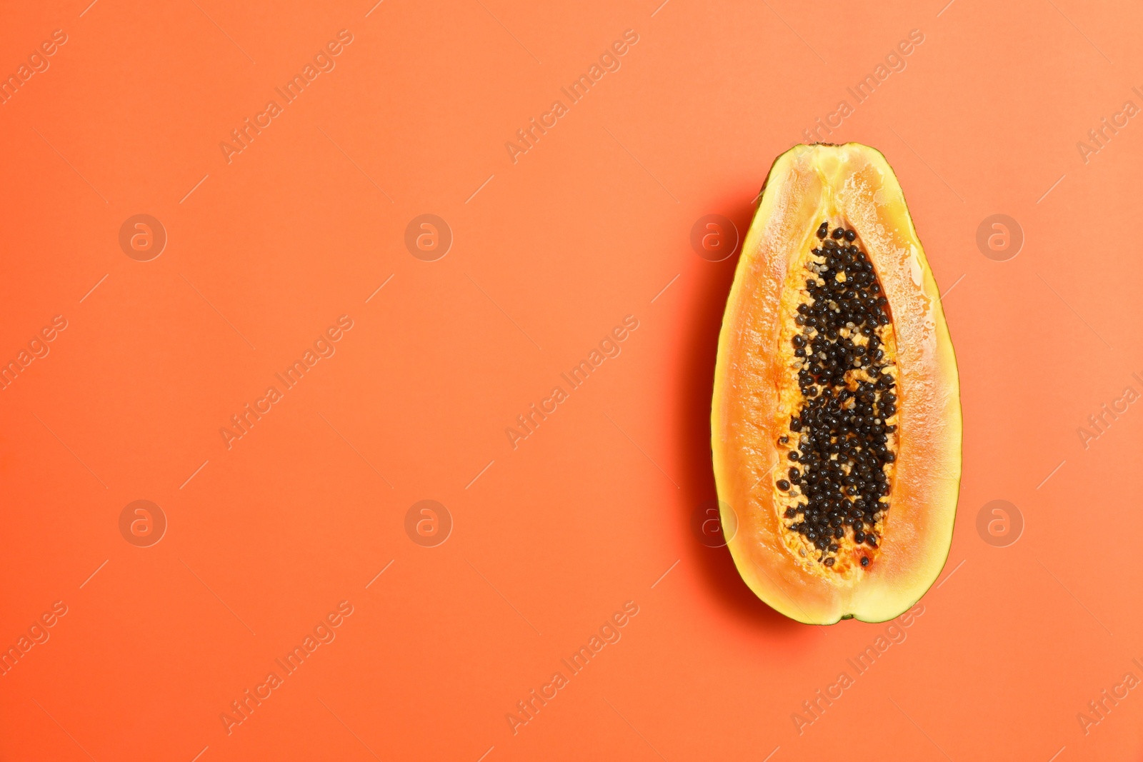 Photo of Fresh juicy halved papaya on coral background, top view. Space for text