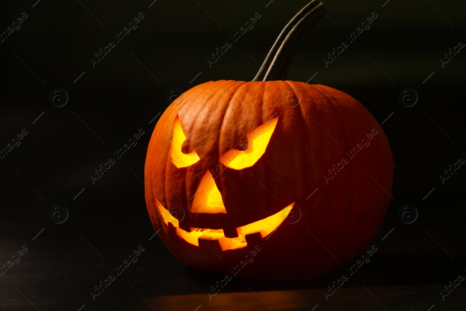 Photo of Scary jack o'lantern pumpkin in darkness. Halloween decor