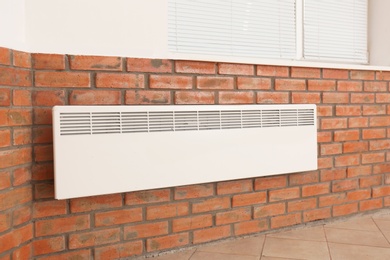 Photo of Modern heating convector on brick wall indoors