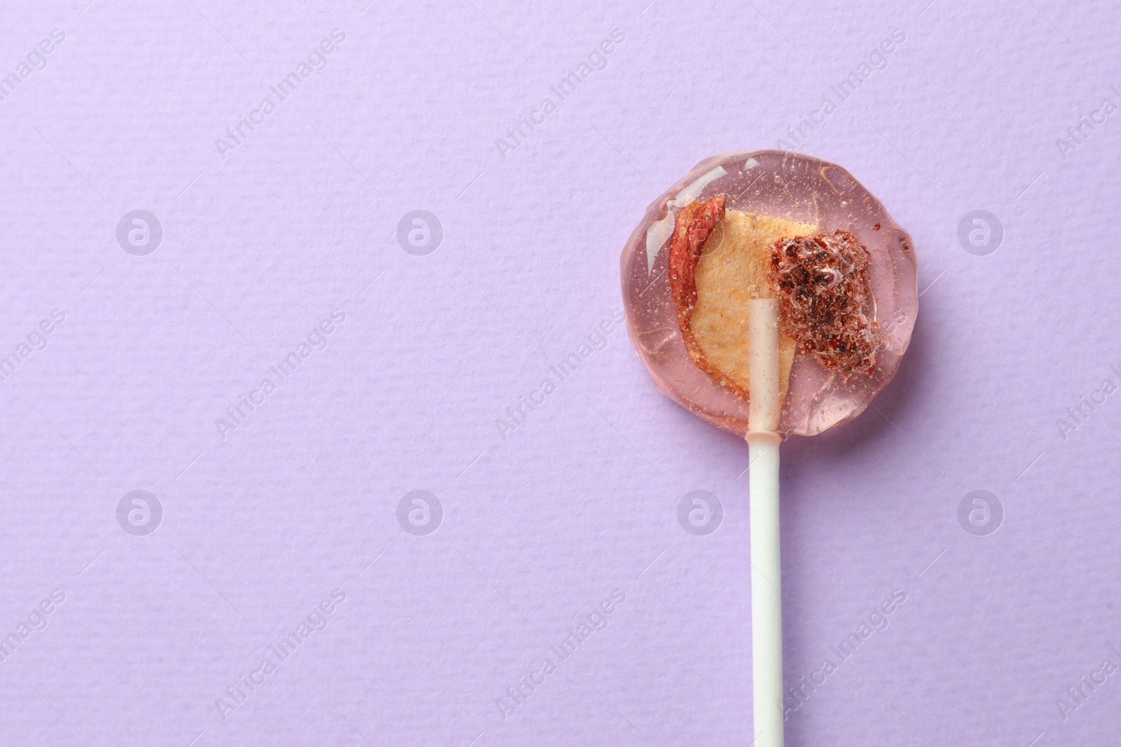 Photo of Sweet colorful lollipop with berries on lilac background, top view. Space for text