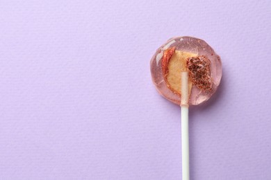 Sweet colorful lollipop with berries on lilac background, top view. Space for text