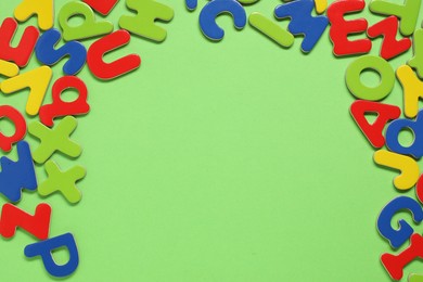 Learning alphabet. Magnetic letters on green background, flat lay. Space for text
