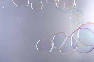 Beautiful transparent soap bubbles on gray background, space for text