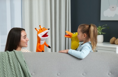 Mother and daughter performing puppet show at home