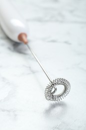 Photo of Milk frother wand on white marble table, closeup