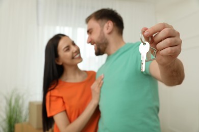 Photo of Happy young couple with key in new house, focus on hand