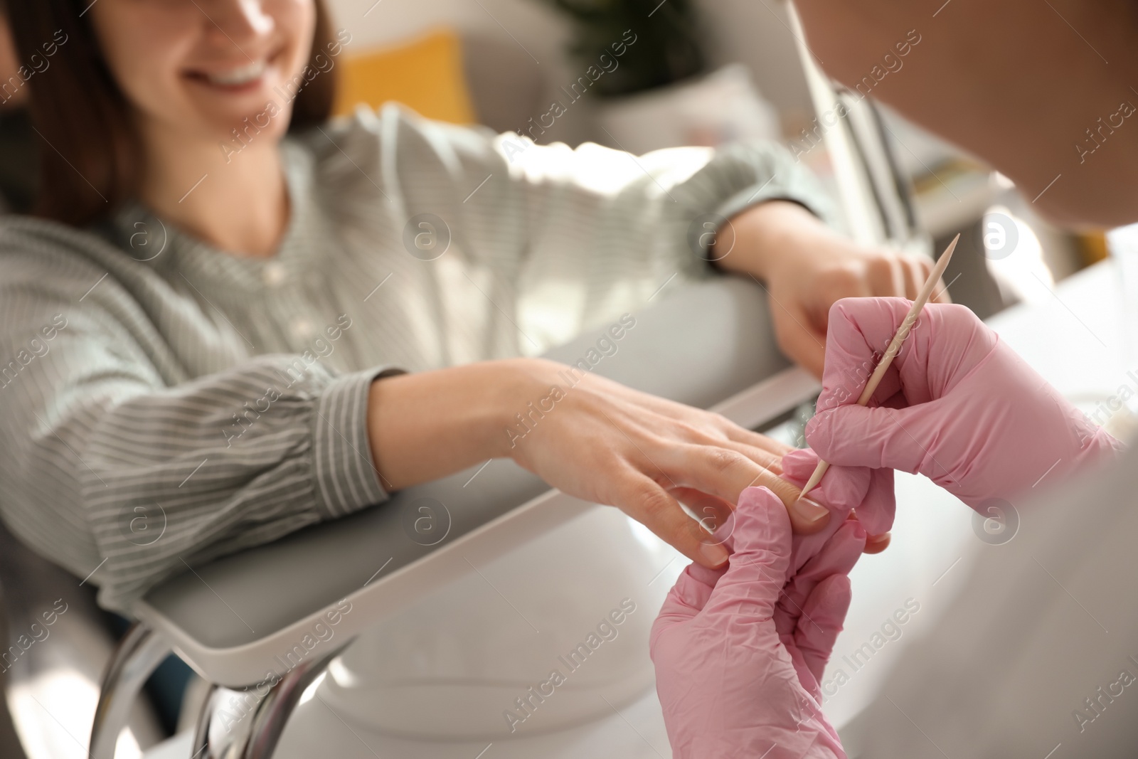 Photo of Professional manicurist working with client in beauty salon, closeup