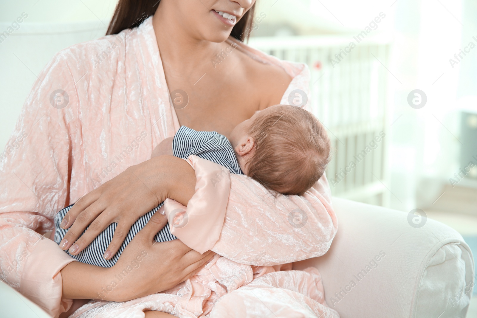 Photo of Young woman breastfeeding her baby in nursery, closeup