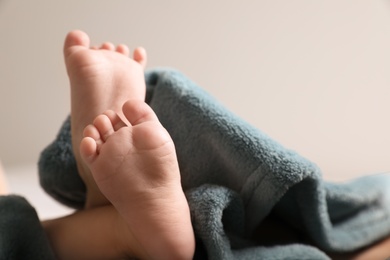 Photo of Little baby lying on soft blanket against light background, closeup. Space for text