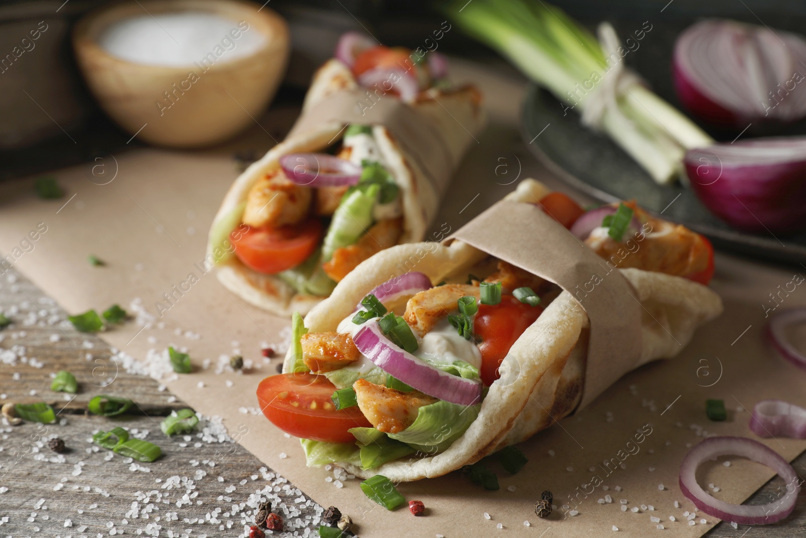 Photo of Delicious pita wraps with meat and vegetables on wooden table, closeup