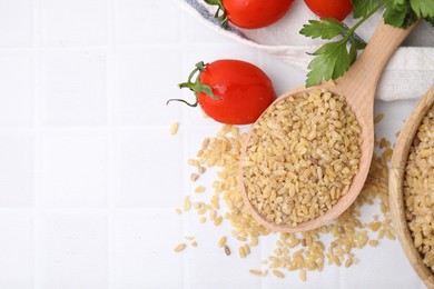 Photo of Raw bulgur, tomatoes and parsley on white tiled table, flat lay. Space for text