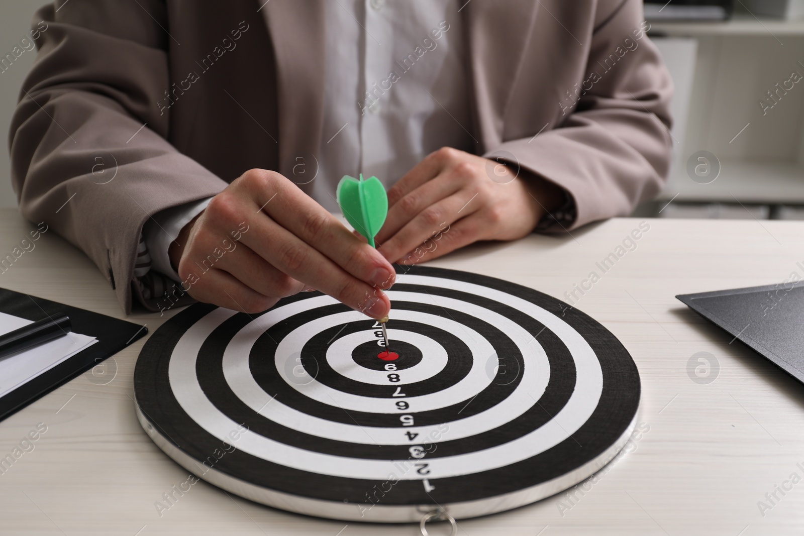 Photo of Business targeting concept. Man with dart aiming at dartboard at table indoors, closeup