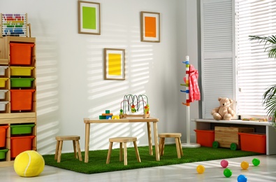 Stylish playroom interior with wooden table and stools