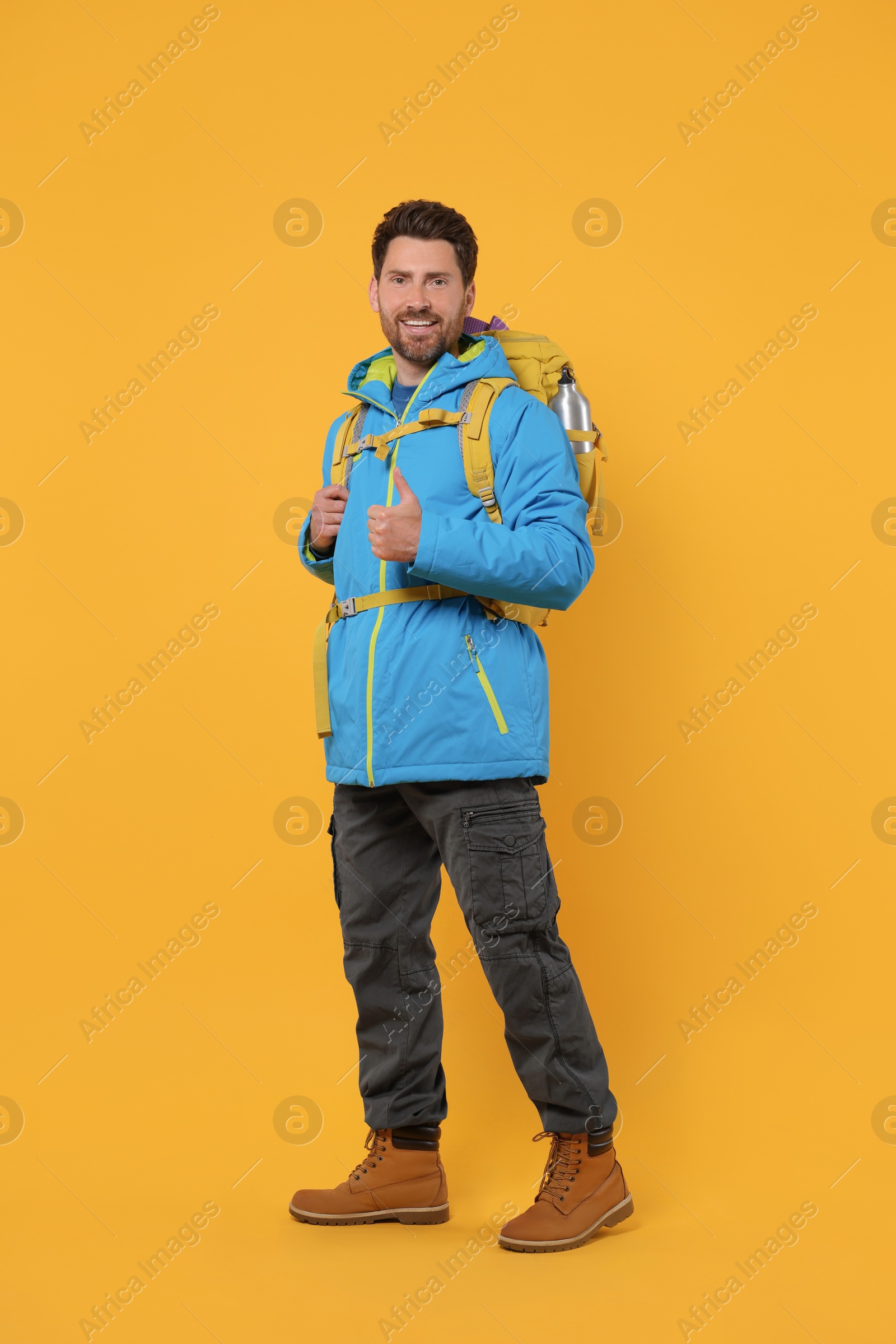 Photo of Happy man with backpack on orange background. Active tourism