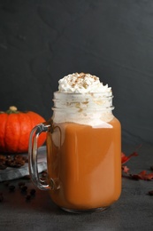 Mason jar with tasty pumpkin spice latte on grey table