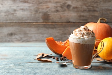 Glass cup with tasty pumpkin spice latte on wooden table. Space for text