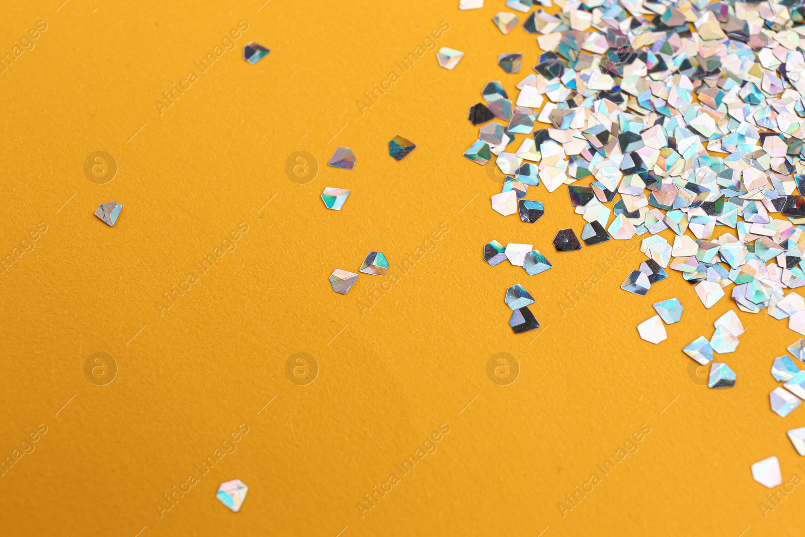 Photo of Shiny bright glitter on orange background. Space for text