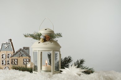 Beautiful composition with vintage Christmas lantern and festive decorations on snow against white background. Space for text