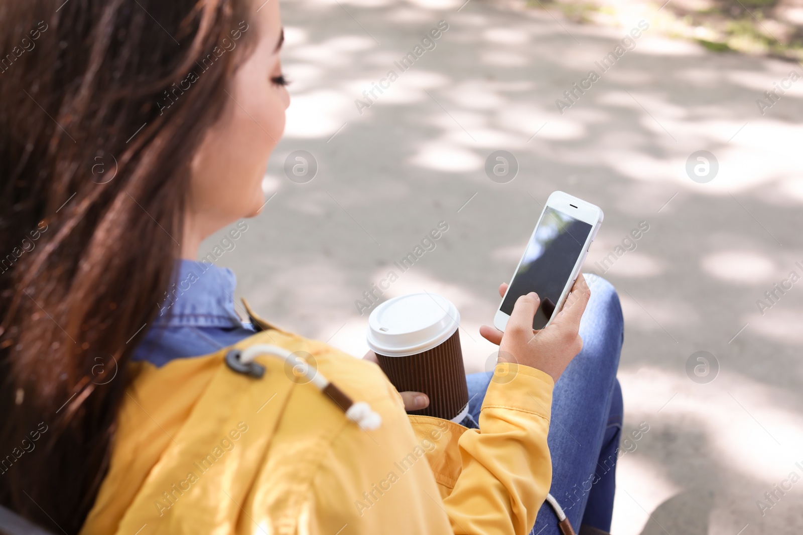 Photo of Young woman using phone outdoors on sunny day