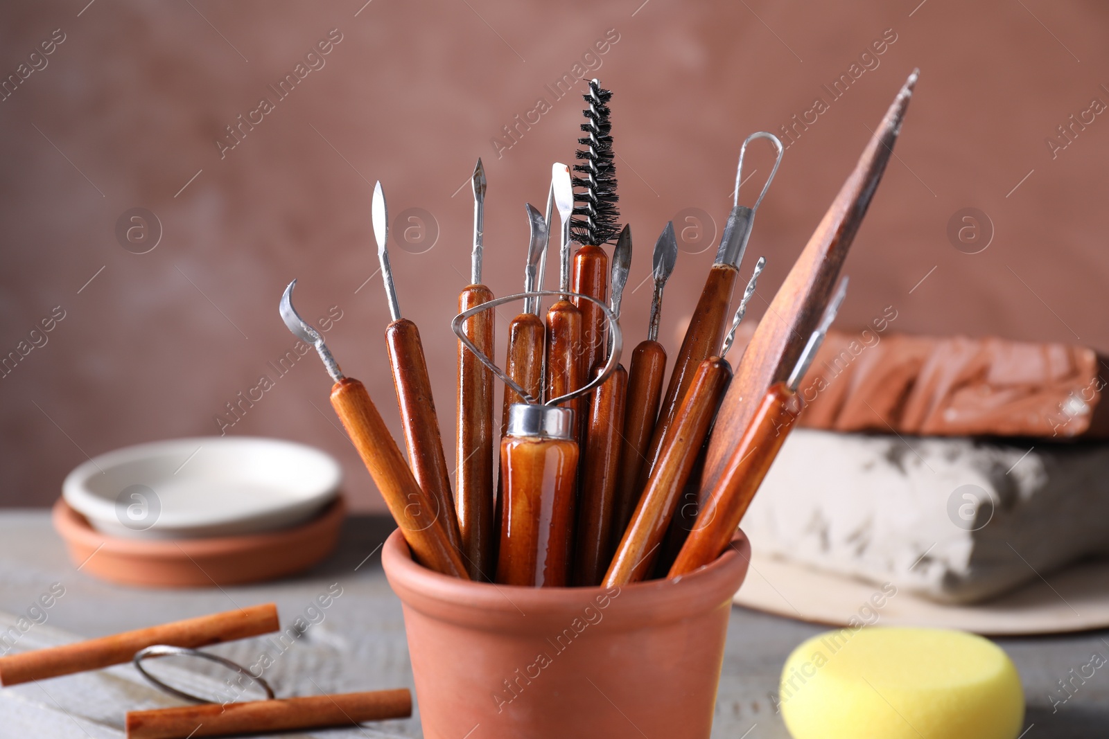 Photo of Clay and set of crafting tools on grey wooden table in workshop, closeup