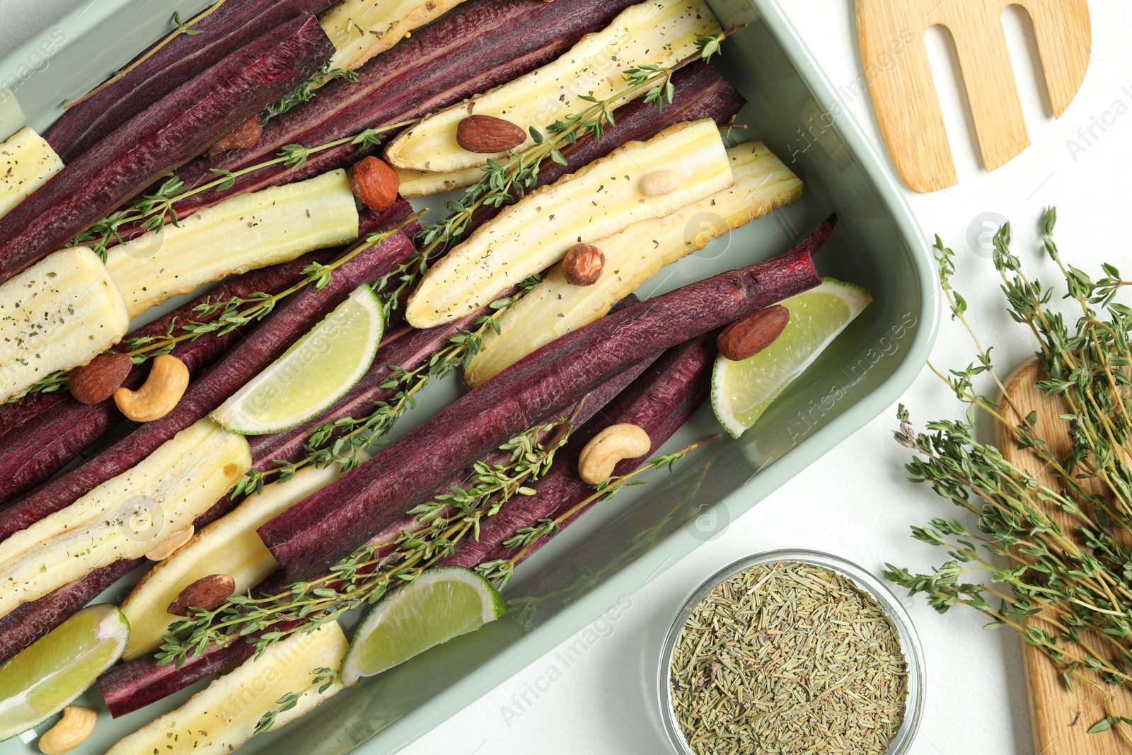 Photo of Flat lay composition with raw cut carrots in baking dish on white table