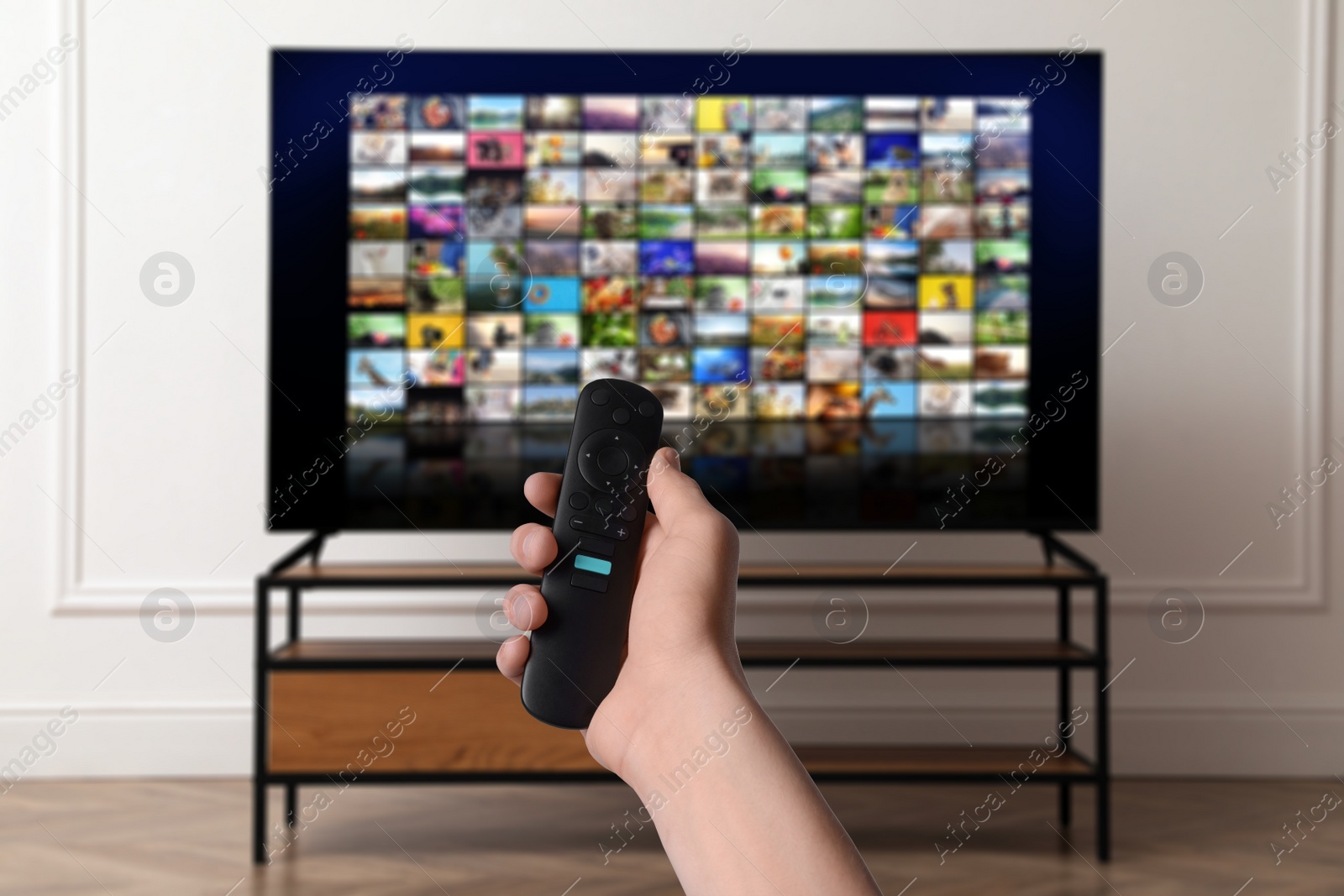 Image of Woman with remote control changing channels while watching TV at home, closeup