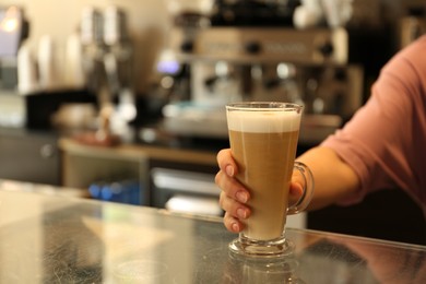 Photo of Barista putting glass with delicious coffee on countertop in cafe, space for text