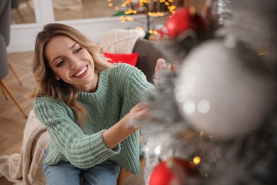 Photo of Young woman decorating Christmas tree at home, above view