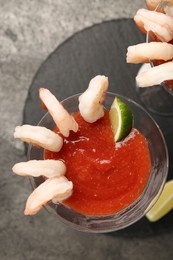 Tasty shrimp cocktail with sauce in glasses and lime on grey table, flat lay
