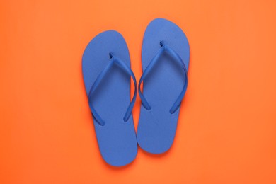 Photo of Stylish blue flip flops on orange background, top view