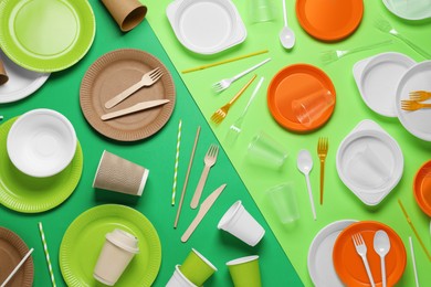 Photo of Flat lay composition with plastic and eco disposable tableware on green background