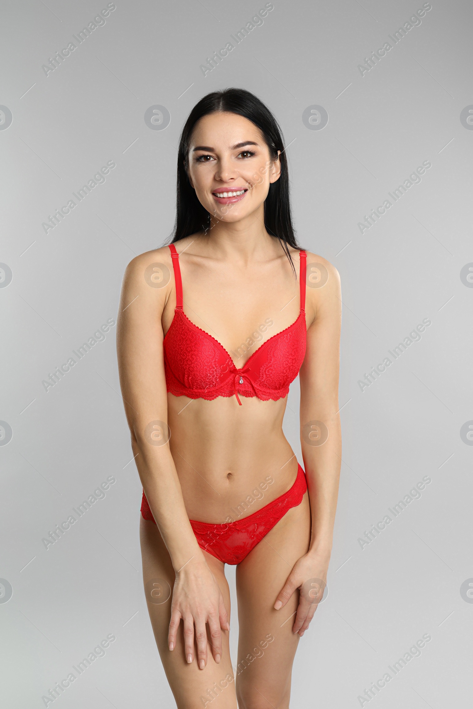 Photo of Beautiful young woman in red underwear on grey background