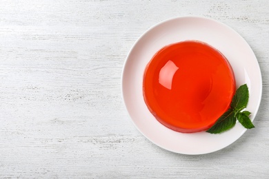 Delicious orange jelly with mint on white wooden table, top view. Space for text