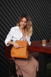 Young woman with stylish backpack in outdoor cafe