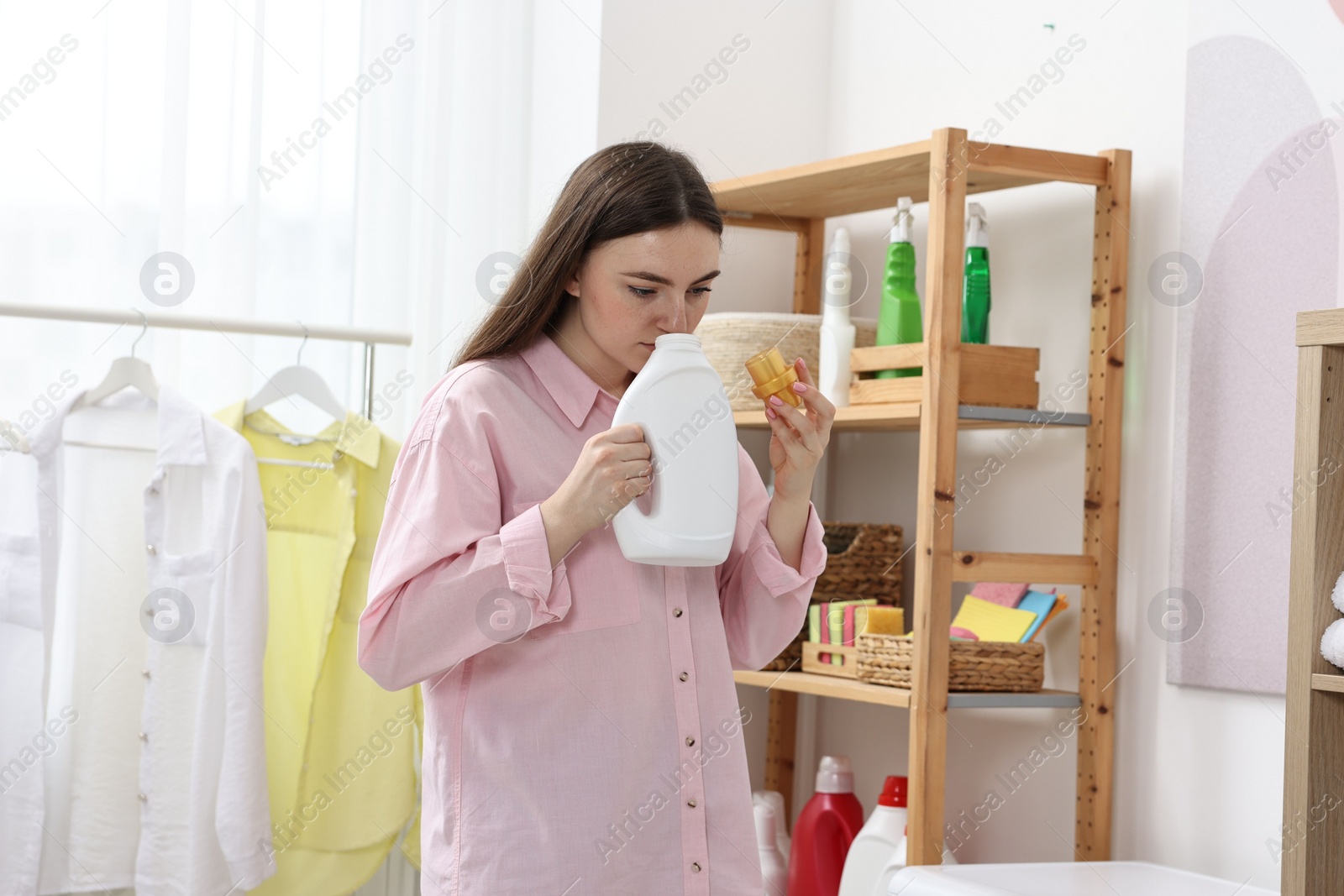 Photo of Beautiful young woman with detergent in laundry room