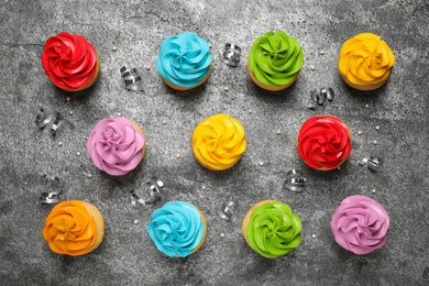 Flat lay composition with colorful birthday cupcakes on grey table